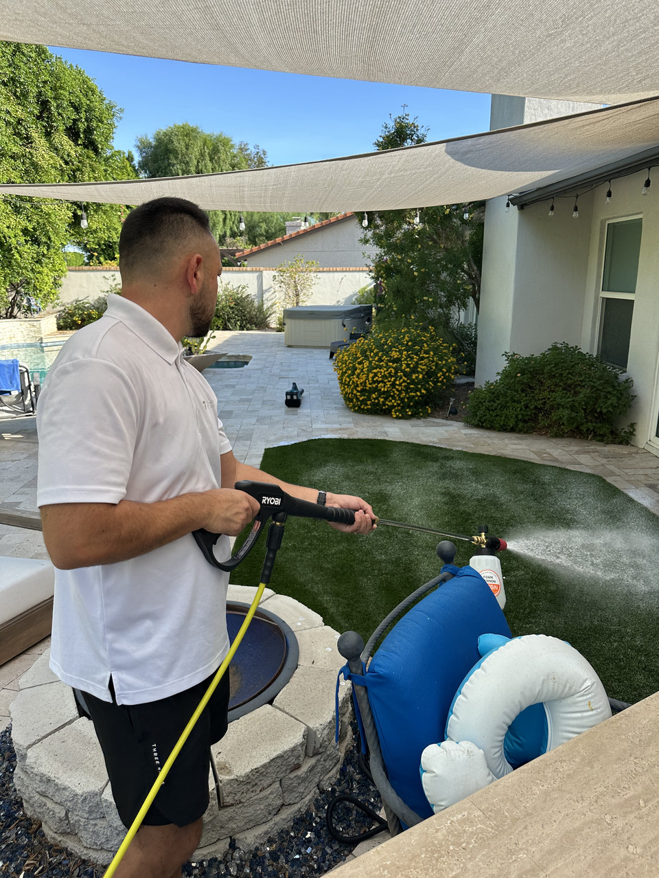 Life Turf technician spraying a cleaning treatment on backyard artificial turf in Arizona