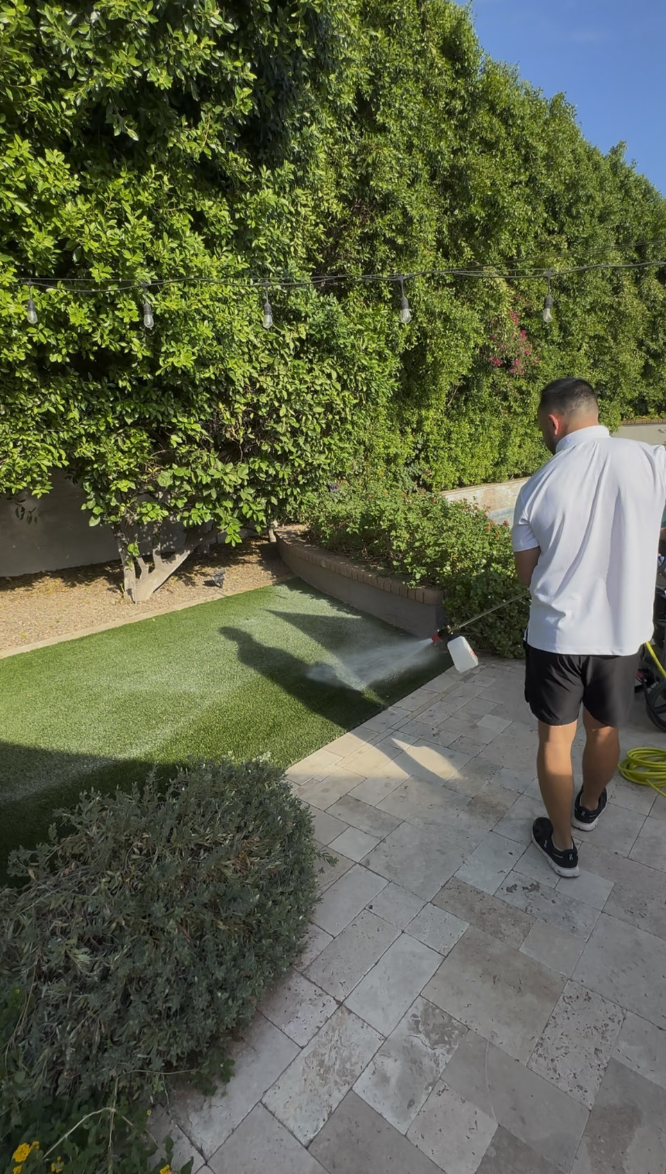 Life Turf technician rinsing artificial turf in a side yard in Arizona