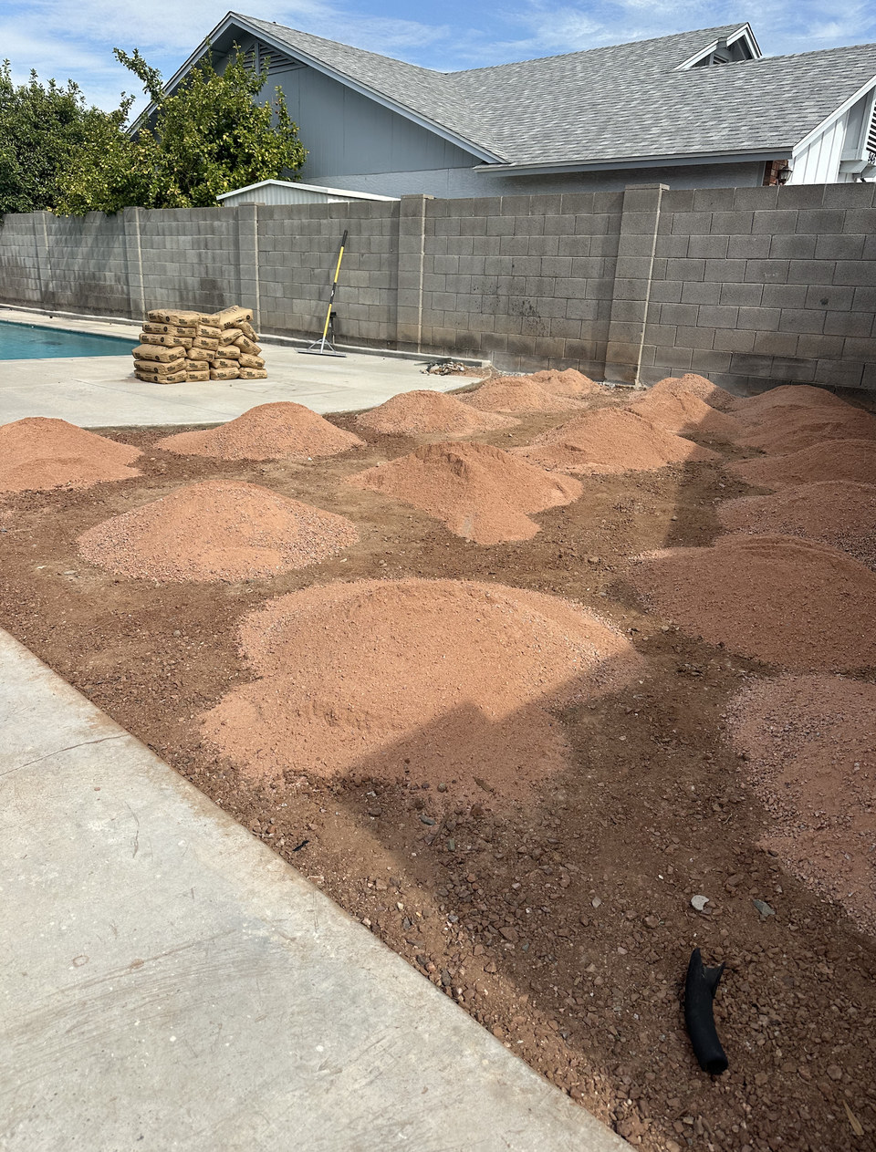 Base material spread across a backyard ahead of an artificial turf install by Life Turf